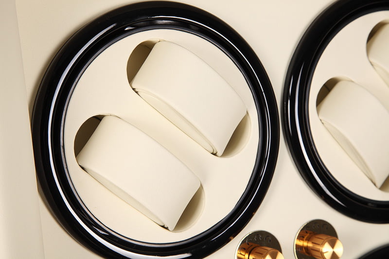 Watch winder close-up showing two beige watch cushions in a black circular winding position