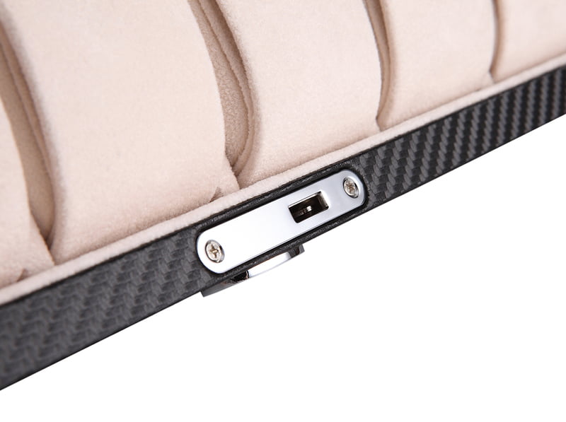 Watch case hardware lock detail beside beige velvet watch cushions
